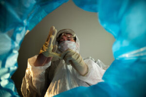 A lab tech removes their PPE that can be picked up by medical waste collection services in Downtown Houston, TX